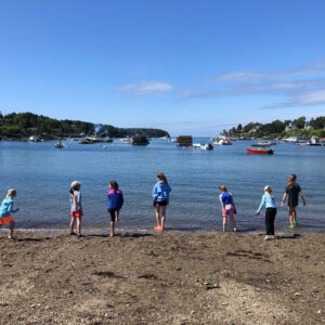 children stand in a row at waters edge