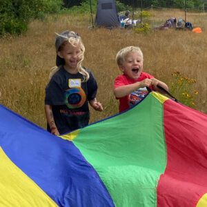children smile as they play with parachute