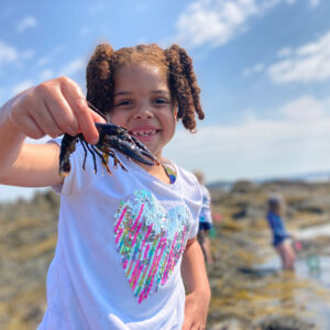 girl smiles holding out baby lobster