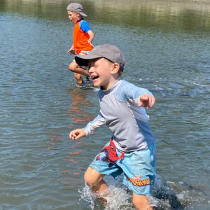 boys run through shallow water laughing