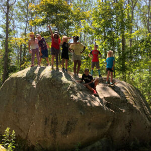 group of children stand on boulder