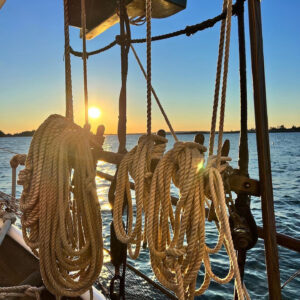 ropes on sailboat with sunset in background