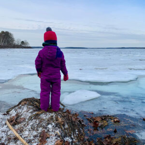 child stands at edge of frozen cove