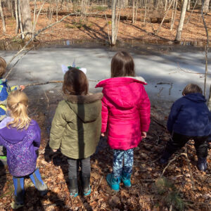 children examine frozen vernal pool