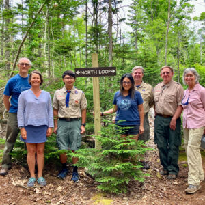 group poses by trail sign