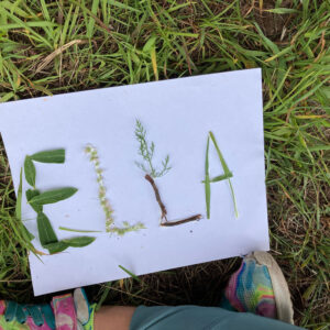 ELLA spelled on paper with grass leaves and flowers