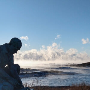 statue with water and clouds in background