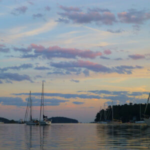 purple clouds over sailboats at sunset