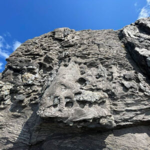 close-up of pockmarked rock with blue sky above