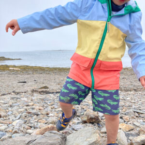 boy walks across pile of rocks at beach