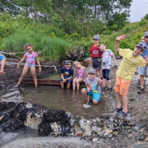 kids building dam across stream stop to look at camera