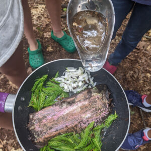 children make "food" in the forest kitchen with wood, water, and greenery