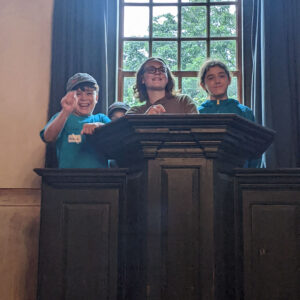 three children smile standing at podium in meeting house