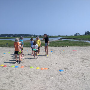 children stand in group surrounded by colorful cones on beach