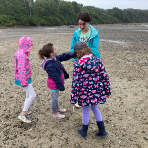 children stand in raincoats at beach