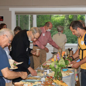 people gather around food table at meeting