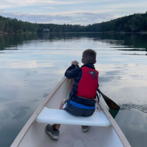 child paddles at front of canoe