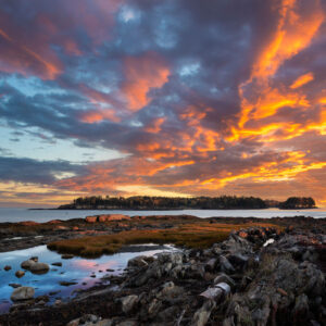 pink and orange sky over rocky shore at sunset
