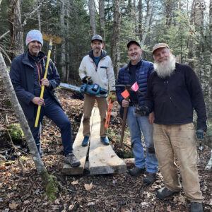 four men smile for camera at trail building day