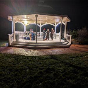 people in lit pavilion at night