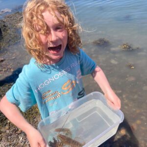 child smiles holding baby lobster