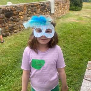 girl smiles at camera holding homemade mask
