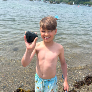 boy smiles and holds up rock for camera