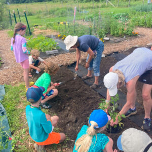 children help plant at community garden