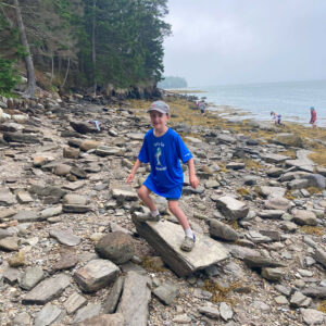 child stands on rock at beach