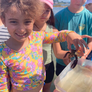 girl holding baby lobster smiles at camera