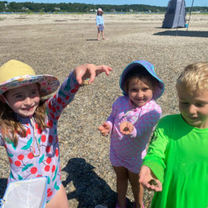 three children holding hermit crabs smile for camera