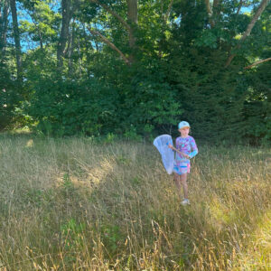 child in field holds butterfly net