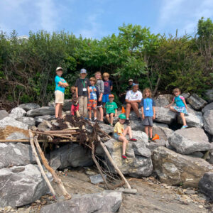 children stand on rocky outcropping of beach