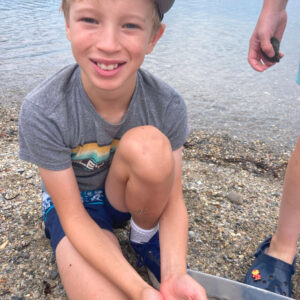 smiling boy holds handful of shells for camera