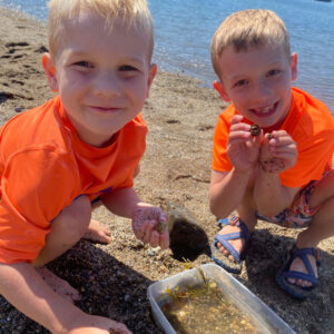 two boys smile around collection bucket