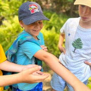 boy smiles as salamander climbs his arm