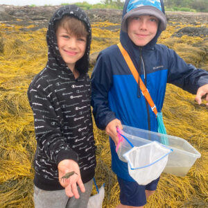 two boys smile for camera while holding crabs