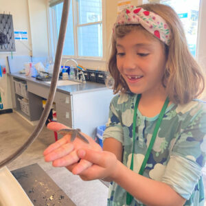 girl smiles while holding sea star over touch tank