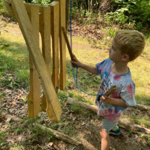 child plays wooden xylophone at forest playground