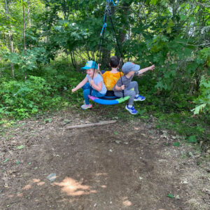 children play on swing at forest playground