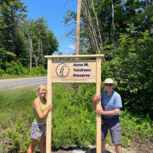 two people stand with new trailhead sign