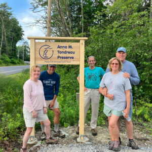 volunteers stand with new Anna M. Tondreau Preserve sign