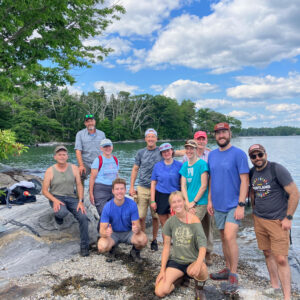 group of people stand on rocks near water and smile for camera