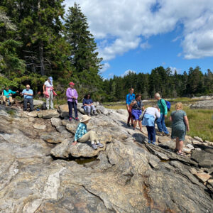 a group of people stand on the rocky shore of an island
