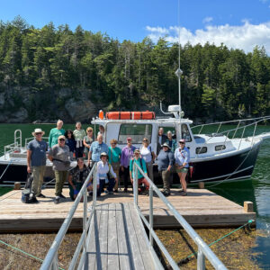 a group smiles on a dock in front of a boat