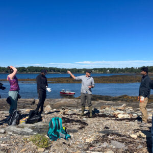 a group stands on an island beach before gathering trash