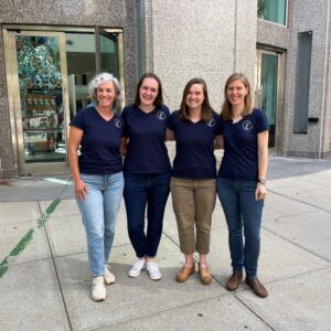 four women smile for camera in matching blue shirts