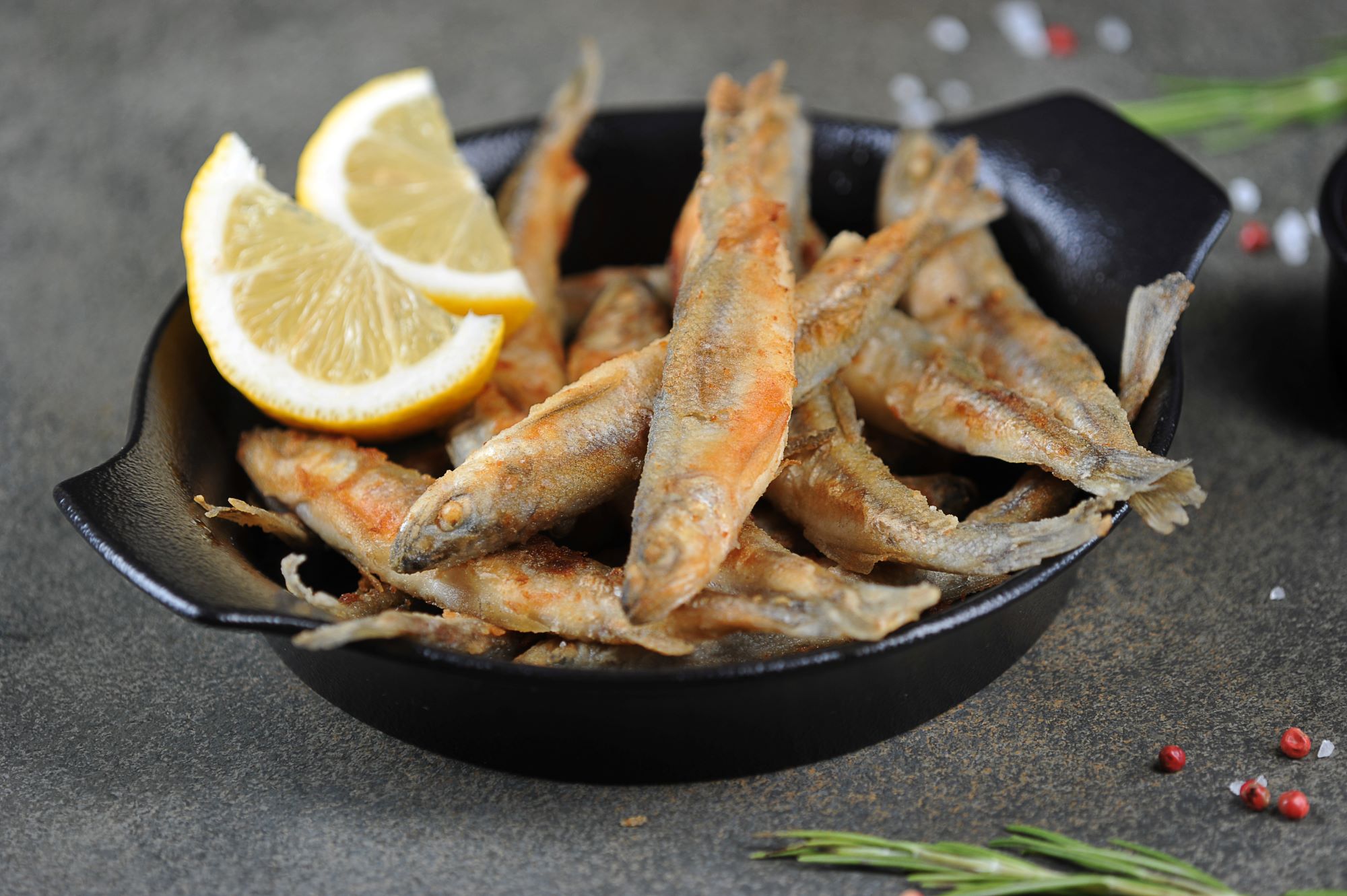fried fish in bowl with two lemon wedges