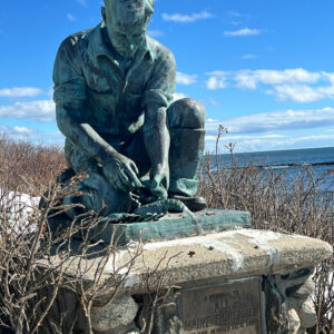 statue of fisherman on stone block with blue sky background