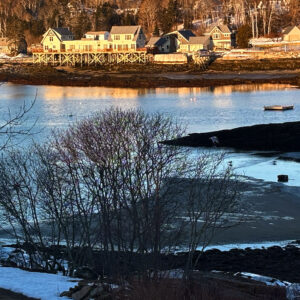 cove with well-lit shoreline on far side at sunset